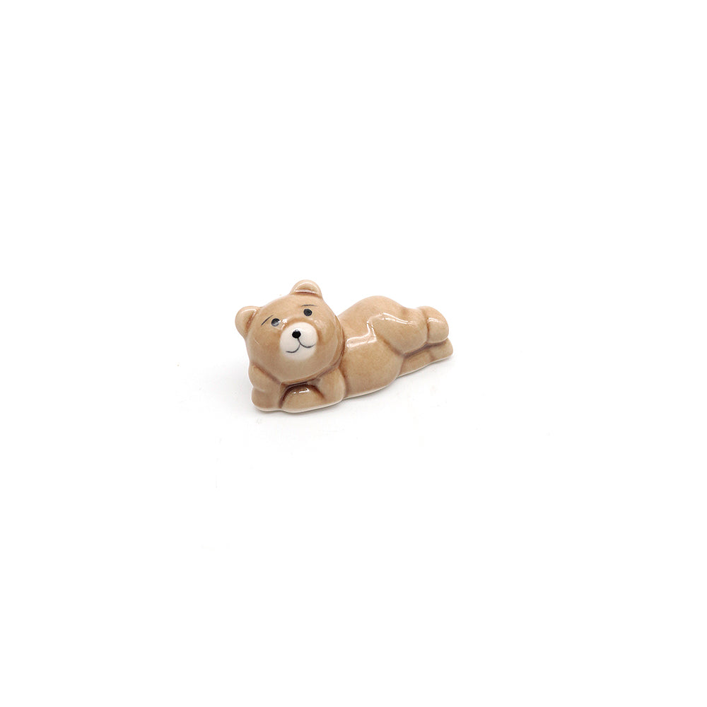 Small tan bear figurine scoop stand lying down on a white background