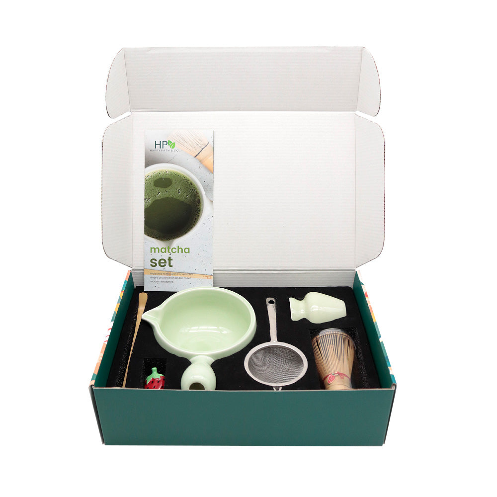 Tea-making set with a green tea box and accessories in an open box on a white background
