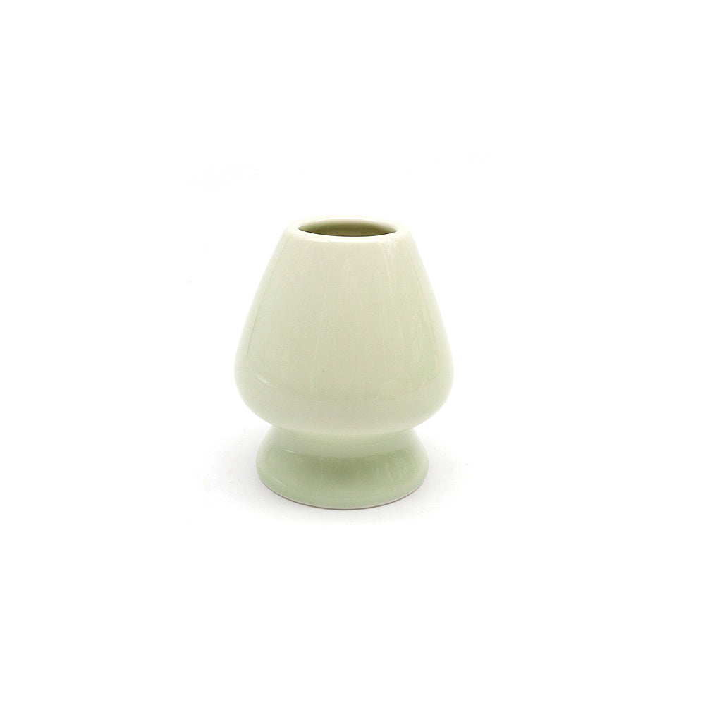 Green ceramic whisk stand on a white background