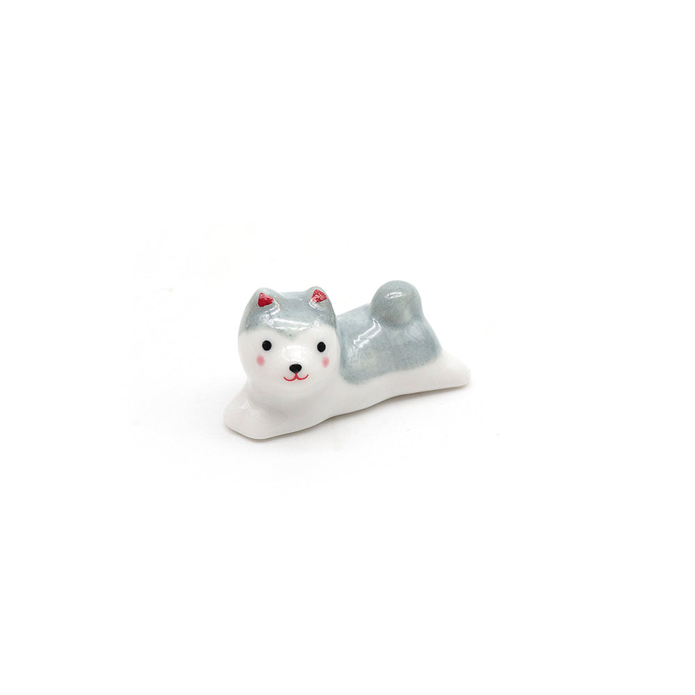 Small ceramic dog puppy figurine scoop stand with a gray back and white front on a white background