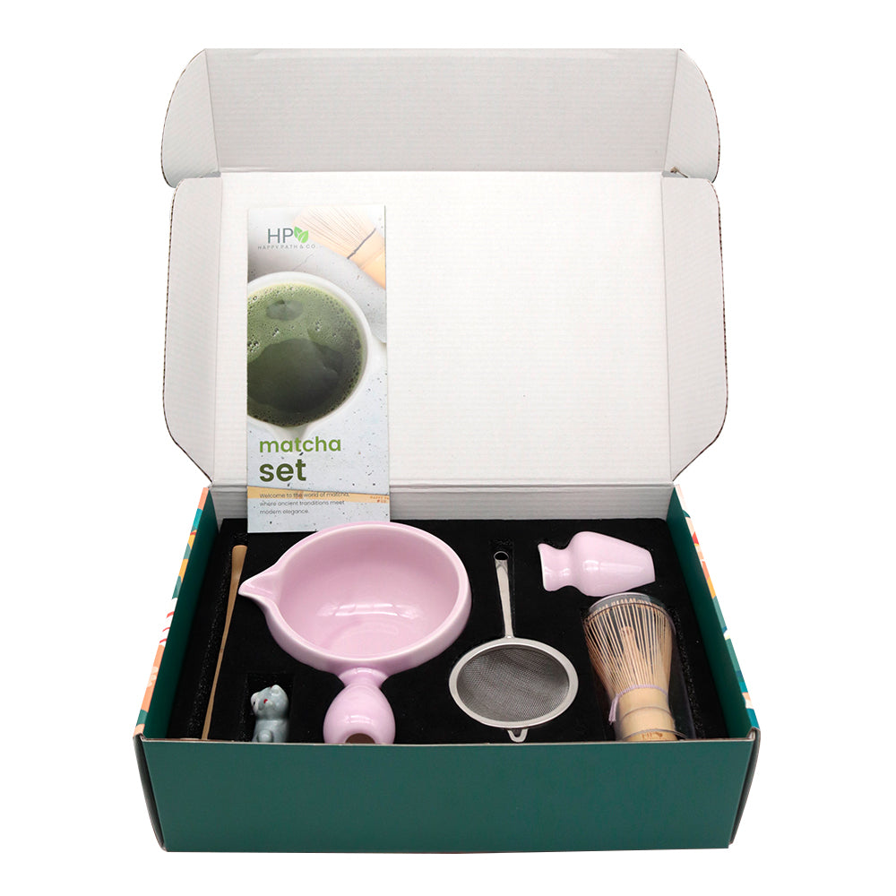 Matcha set with light purple bowl, bamboo whisk and other tools in an open box on a white background
