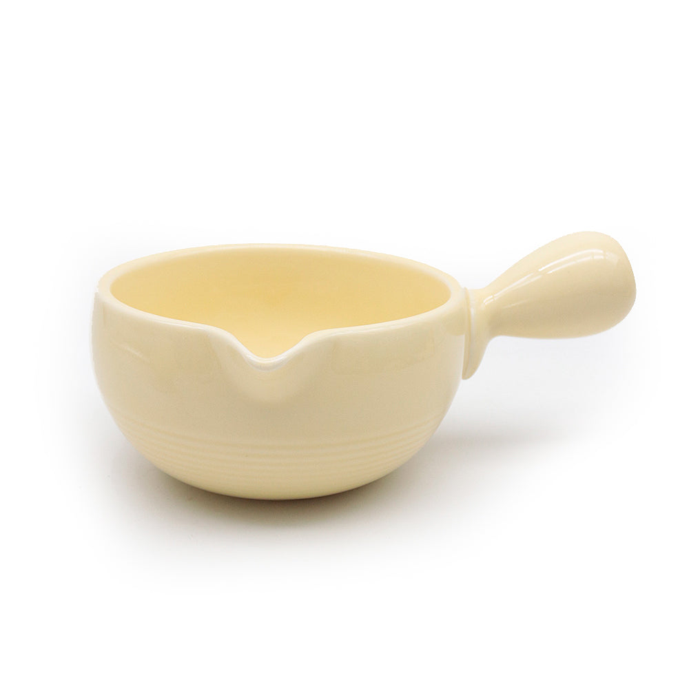 Cream yellow-colored ceramic bowl chawan with handle on a white background