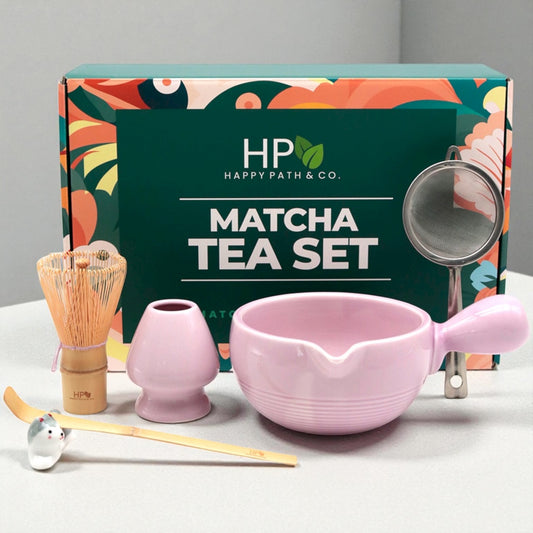 Matcha tea set with light purple bowl, whisk, and other tools in front of Happy Path & Co. gift packaging.