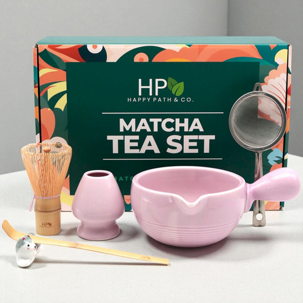 Matcha tea set with light purple bowl, whisk, and other tools in front of Happy Path & Co. gift packaging.